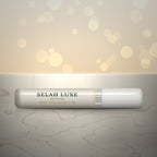Front of the Selah Luxe Official Mini Pro Glue, 2 g tube, on a cream marble surface