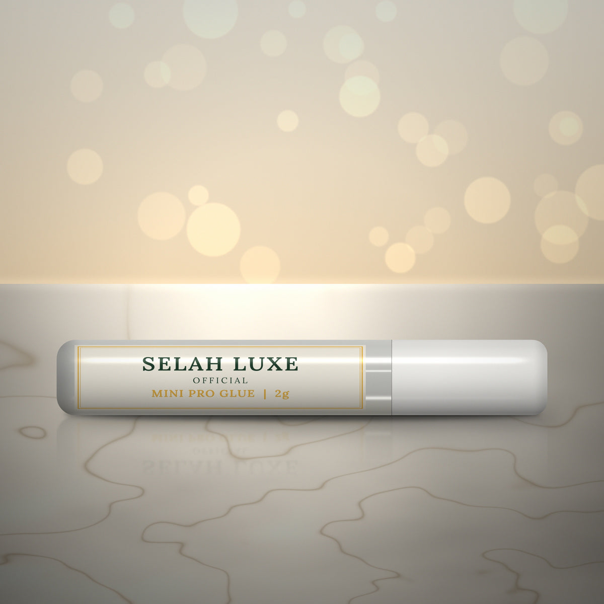 Front of the Selah Luxe Official Mini Pro Glue, 2 g tube, on a cream marble surface
