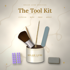 Selah Luxe Official tool kit with a brush, cuticle tools, nail file, buff block and adhesive pads around a cream container.